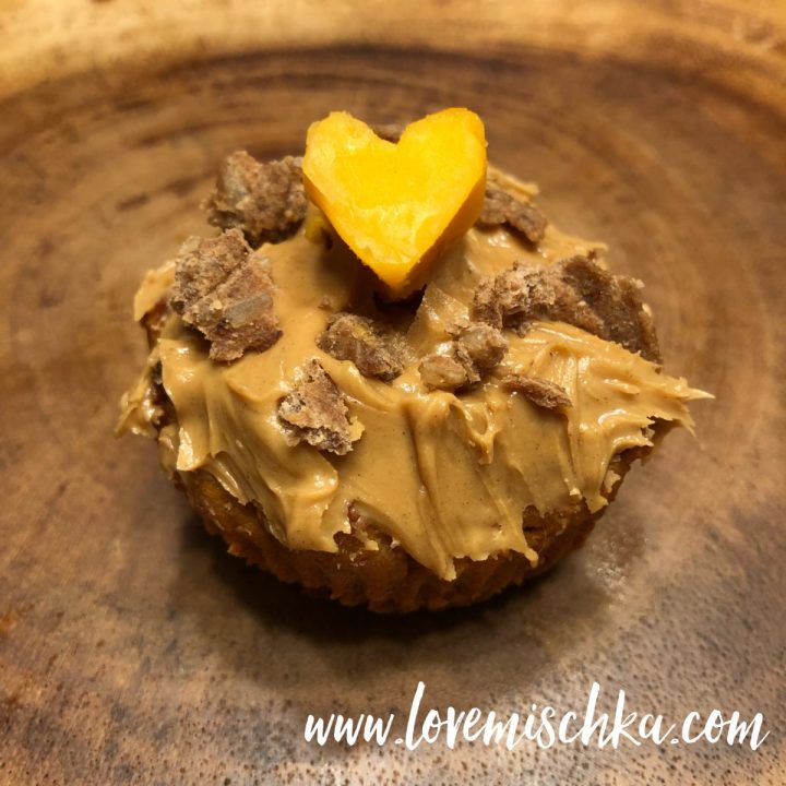 A Dog Cupcake topped with peanut butter and a heart-shaped piece of cheese.