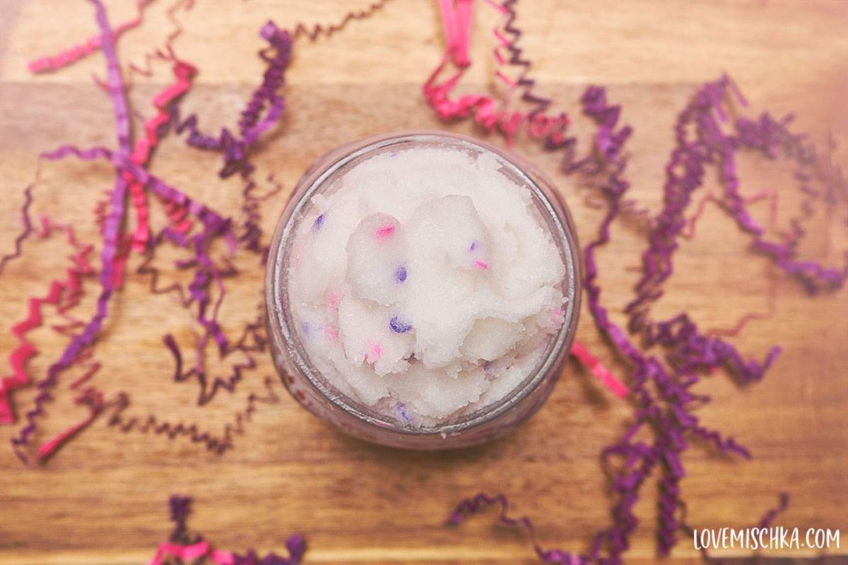 Looking down on white DIY Sugar Scrub with lavender and pink confetti in a mason jar.