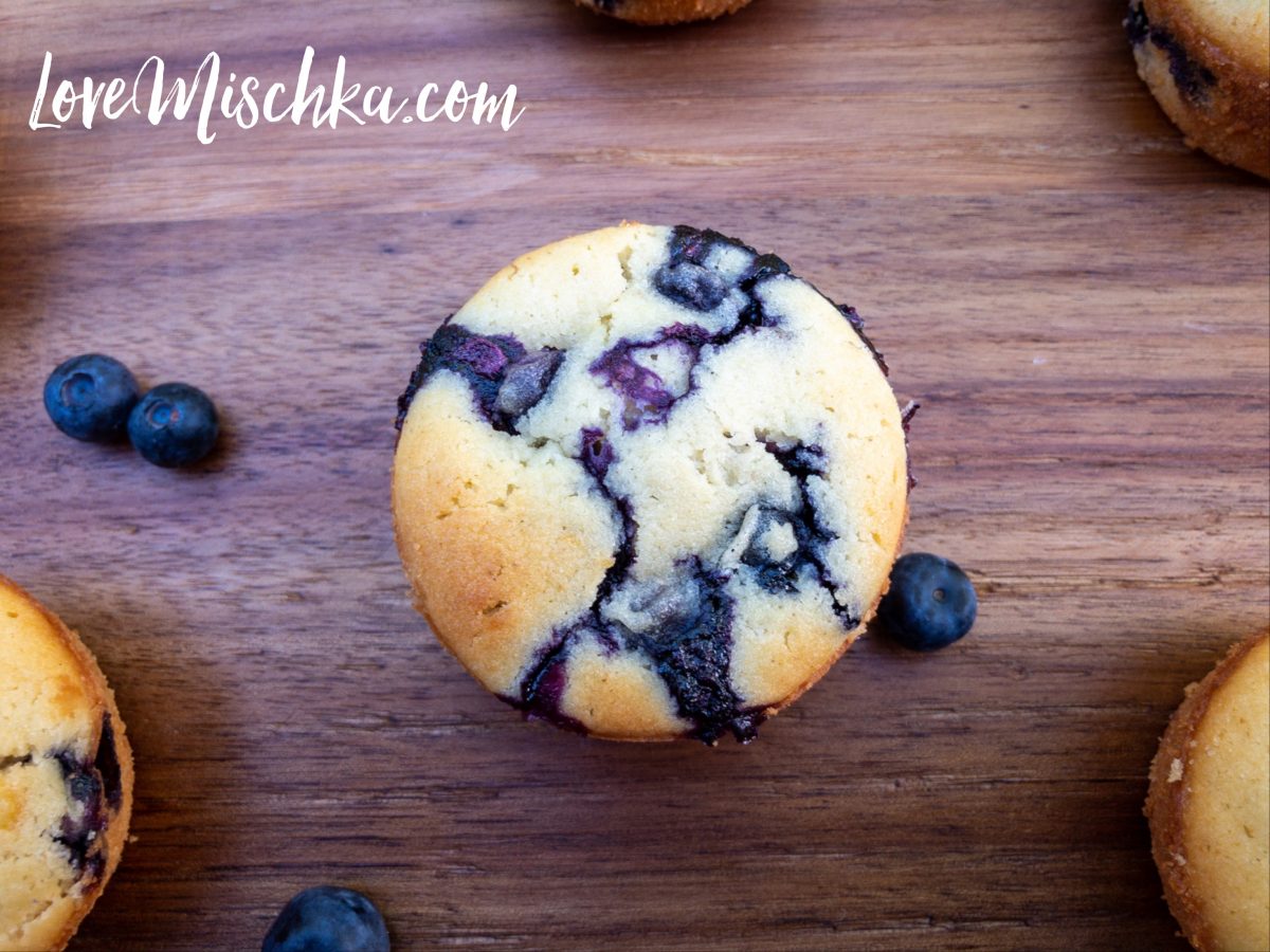 Looking down on a beautiful blueberry lemon muffin. Bright blue blueberries pattern the light tan muffin