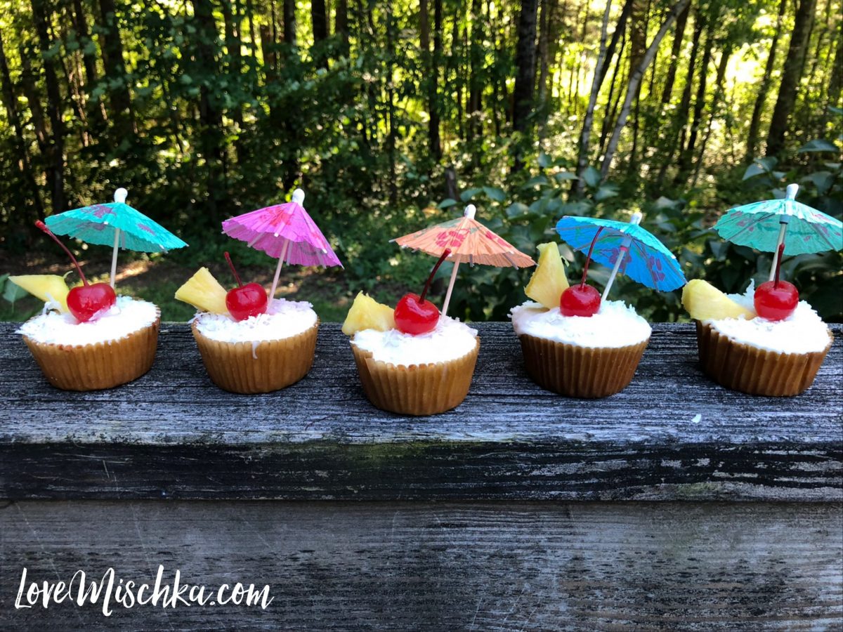 5 Tropical Cupcakes, each has a bright, neon cocktail umbrella and a red maraschino cherry.