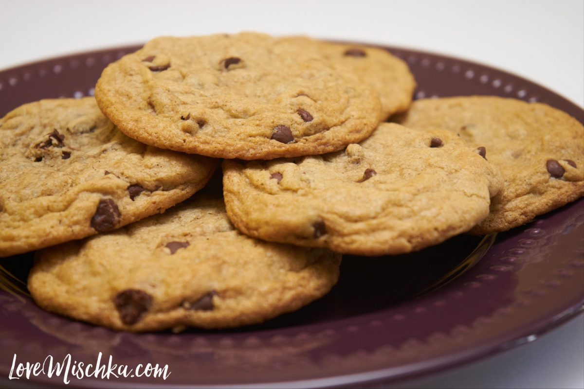A purple plate full of thin, chewy gluten free chocolate chip cookies.