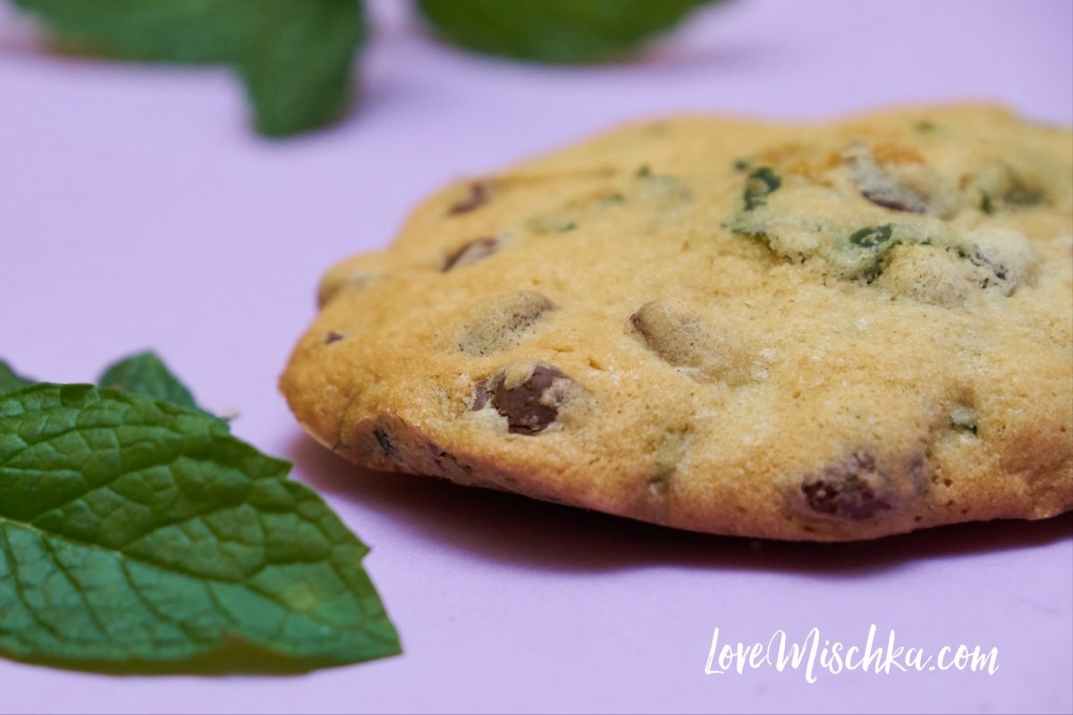 One tan cookie with bright green fresh mint and gooey chocolate chips