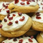 A stack of Cranberry Bliss Cookies with Cream Cheese frosting and chopped dried cranberries.