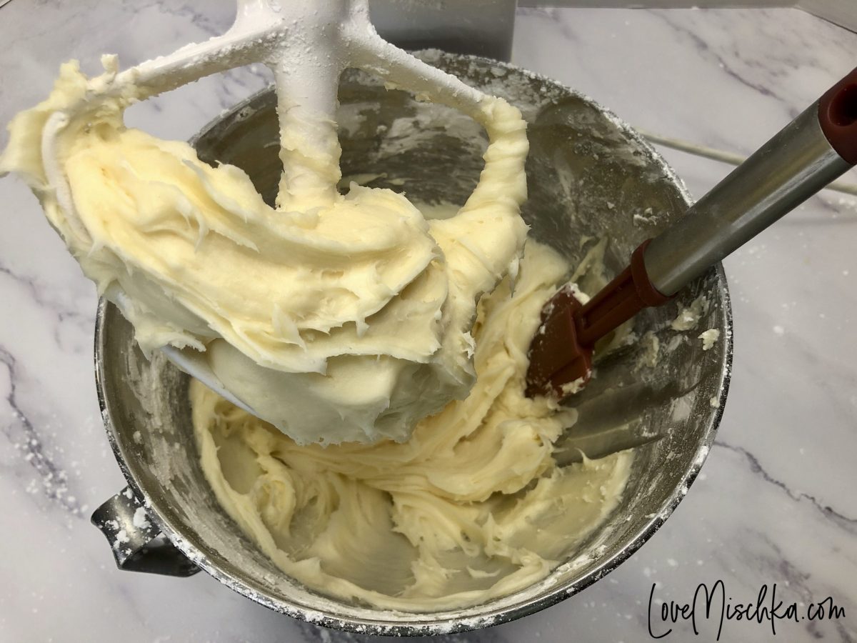 A stand mixer in the process of making fluffy cream cheese frosting.