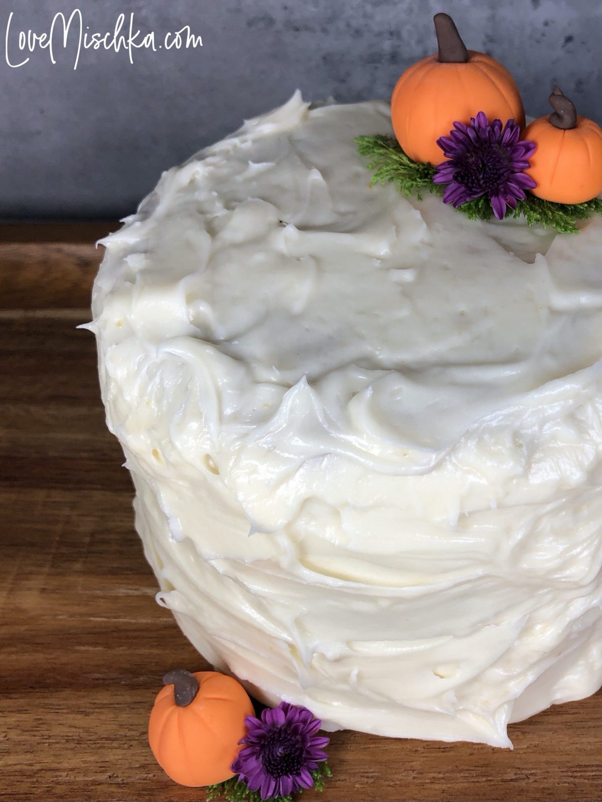 Round Cake with White Creamy Frosting and two small pumpkins.