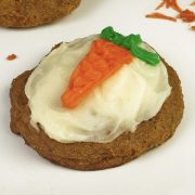 One Carrot Cake Cookie with white cream cheese frosting and an orange carrot made out of frosting with a green stem.