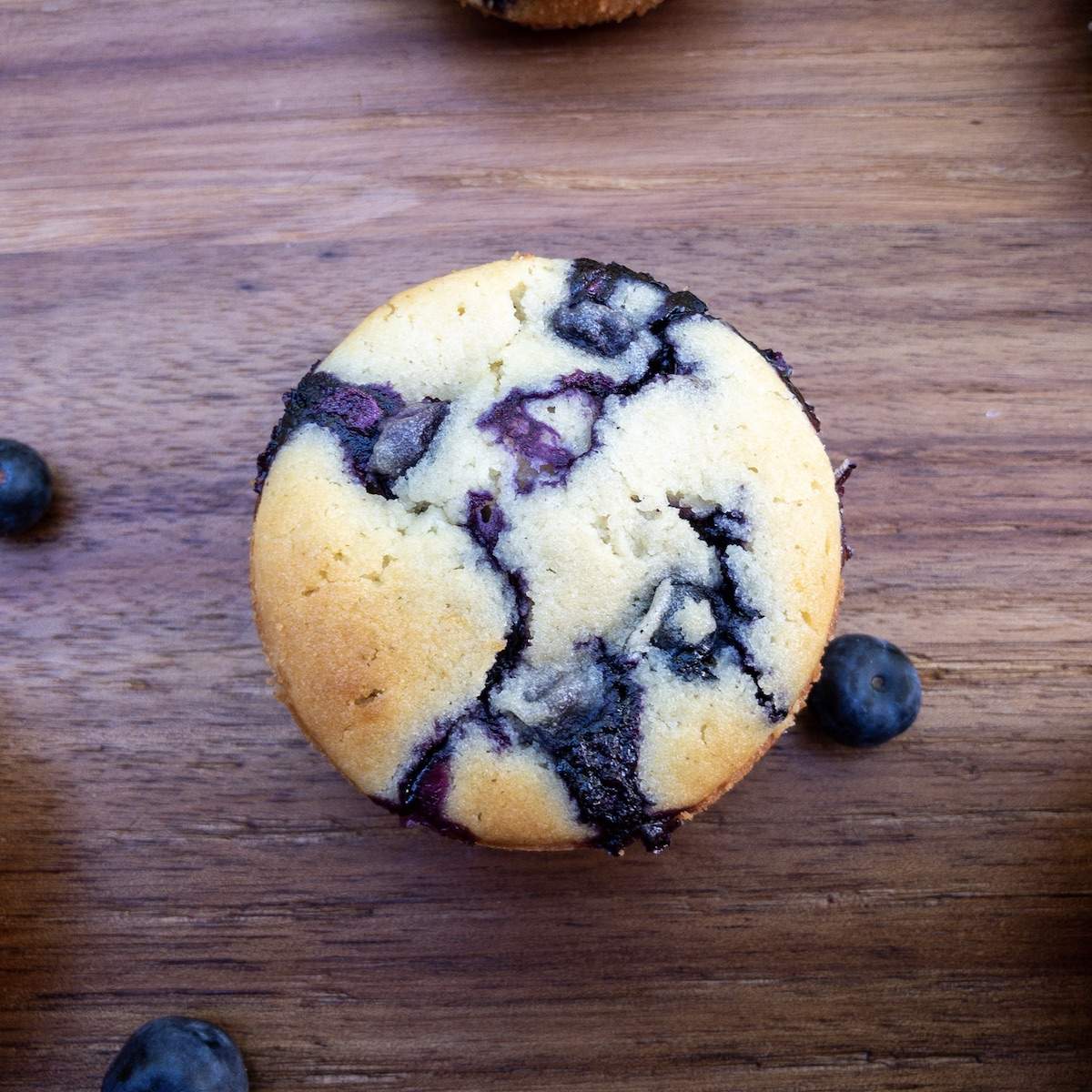 Looking down on a beautiful lemon beautiful muffin with blueberries scattered around.