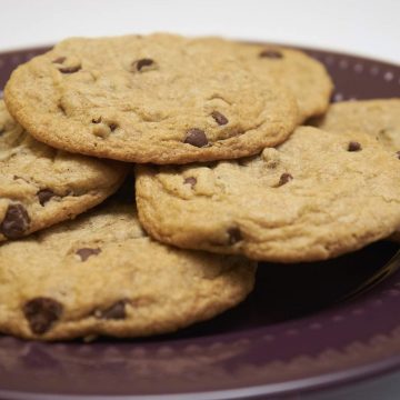 Crispy Gluten-free chocolate chip cookies on a dark purple plate.