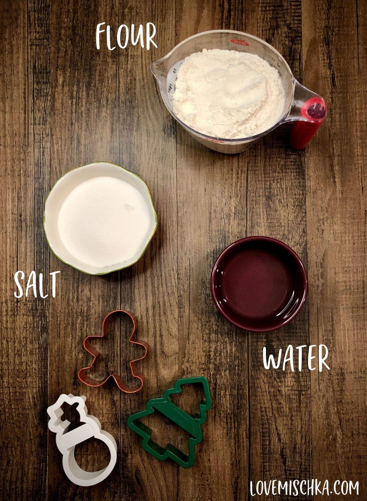 Ingredients for Salt Dough Ornaments (Flour, Salt, and Water) on a table with holiday cookie cutters.