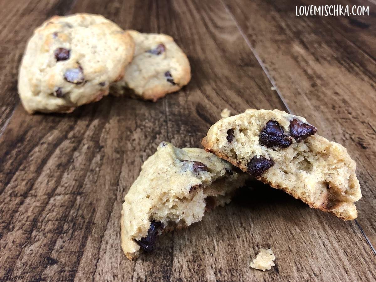 A tan, fluffy banana cookie split in two, showing the delicious chocolate and moist inside. 