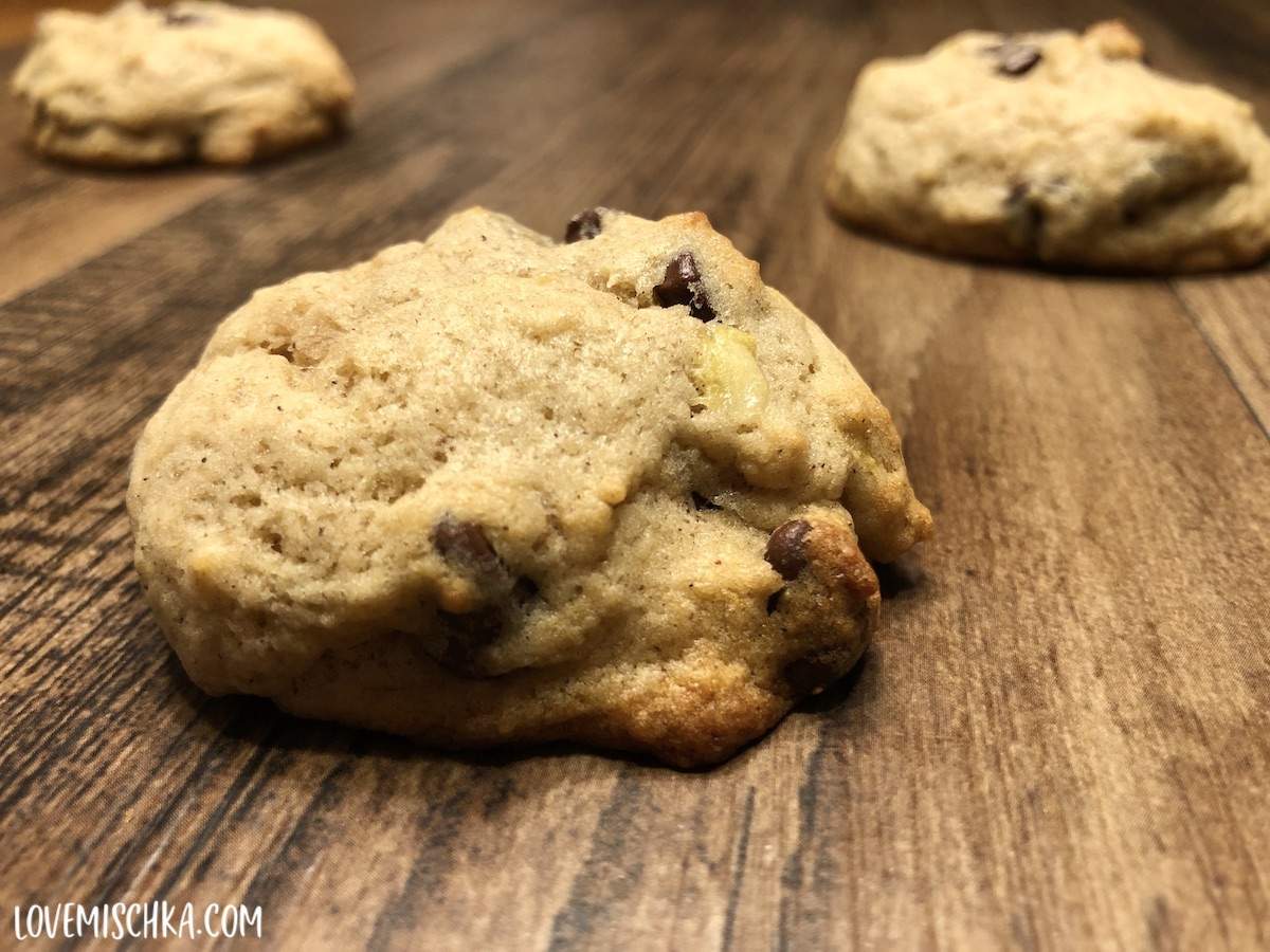 Soft Banana Bread Cookies with brown chocolate chips and yellow banana pieces on a wooden table.