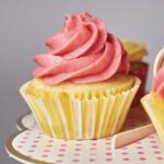 A yellow, lemon cupcake with a pink swirl of blackberry buttercream on top.