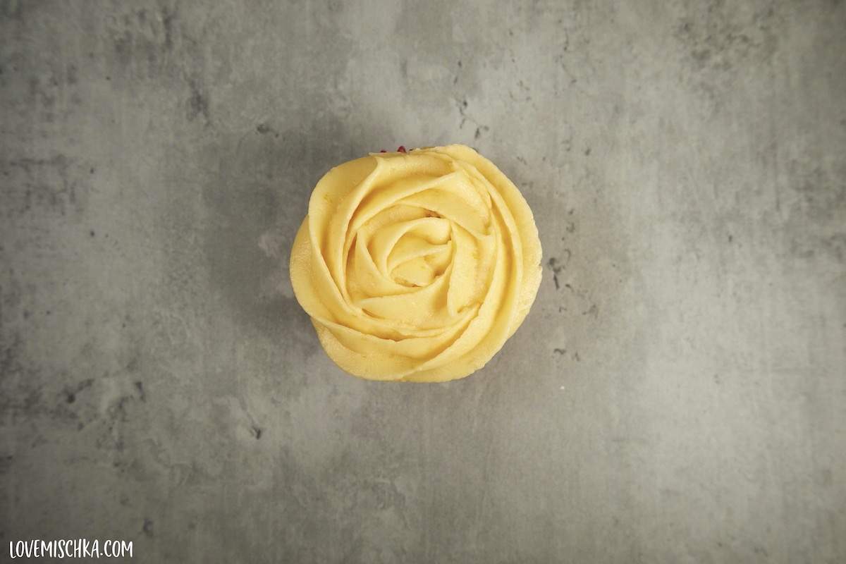 looking down on orange buttercream piped into a rose.