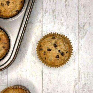 Golden Banana Bread Chocolate Chip Muffins, freshly baked, are still in a silver baking pan.