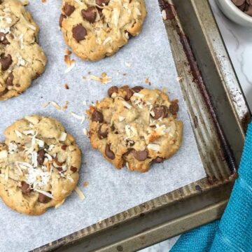 Coconut Chocolate Chip Cookies on top of a parchment-lined, old baking sheet.