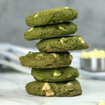 A stack of bright green matcha green tea cookies with white chocolate chips on a marble counter.