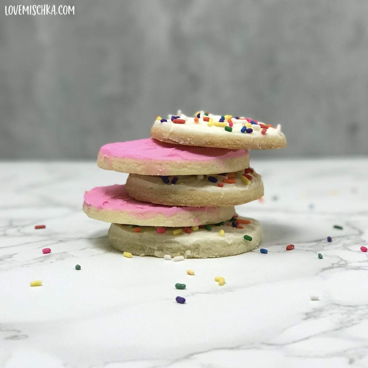 Round Sugar Cookies topped with this Buttercream Frosting Recipe for Cookies are stacked on top of one another.