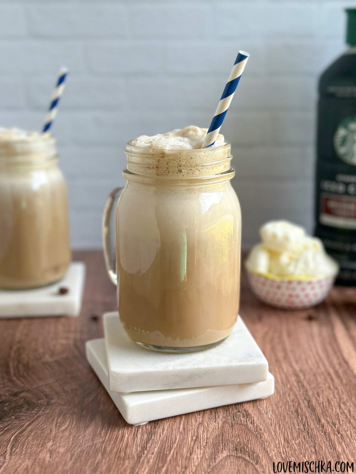 A cold, creamy iced coffee with ice cream in front of the three ingredients in this iced coffee recipe with ice cream - iced coffee, milk, and ice cream.
