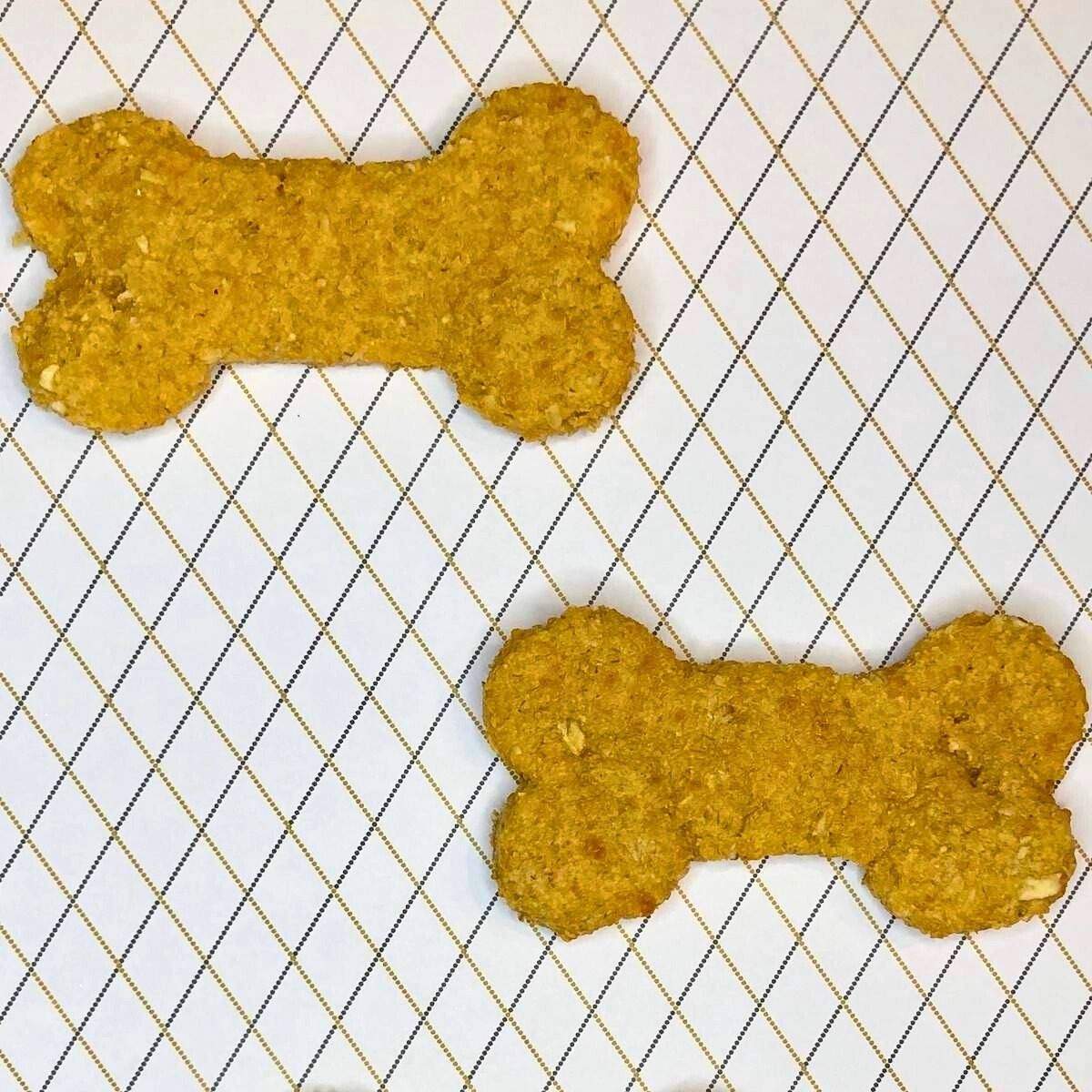 Two bone-shaped, crunchy, yellow cheddar cheese dog treats.