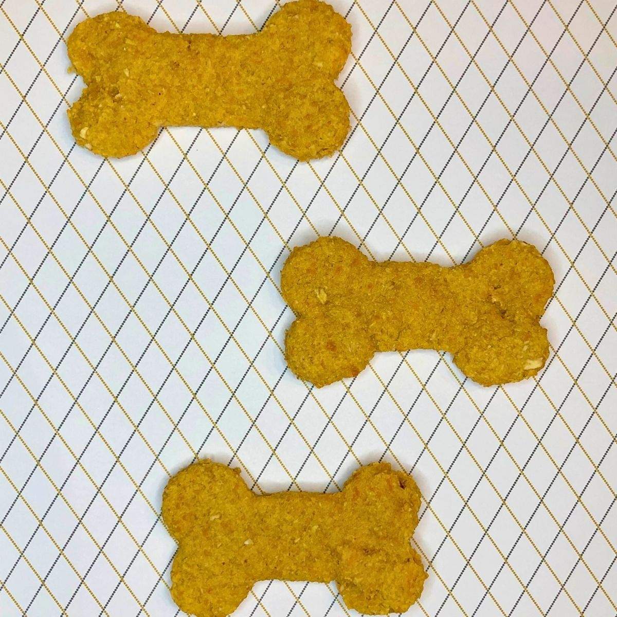 Three golden, bone-shaped cheese dog biscuits in this Cheese Dog Treat Recipe.