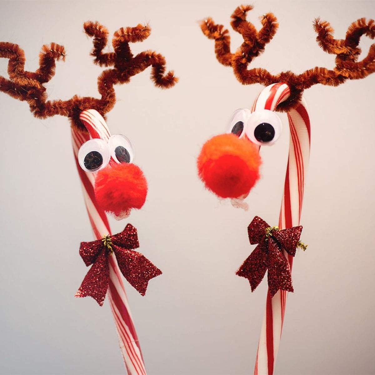 Two reindeer made out of candy canes with googly eyes, red pom pom noses, sparkly red bows, and twisted brown antlers out of pipe cleaners.