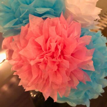 Close-up of a pretty pink DIY Tissue Paper Flower in a bouquet of baby blue and white paper flowers (with tissue paper) in this guide on making tissue paper flowers.