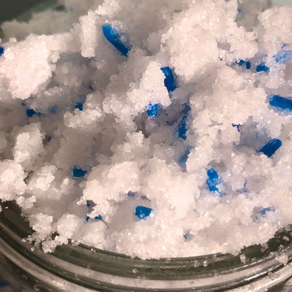 A close-up of overflowing, white, fluffy, homemade body scrub with blue sprinkles in this easy sugar scrub recipe.