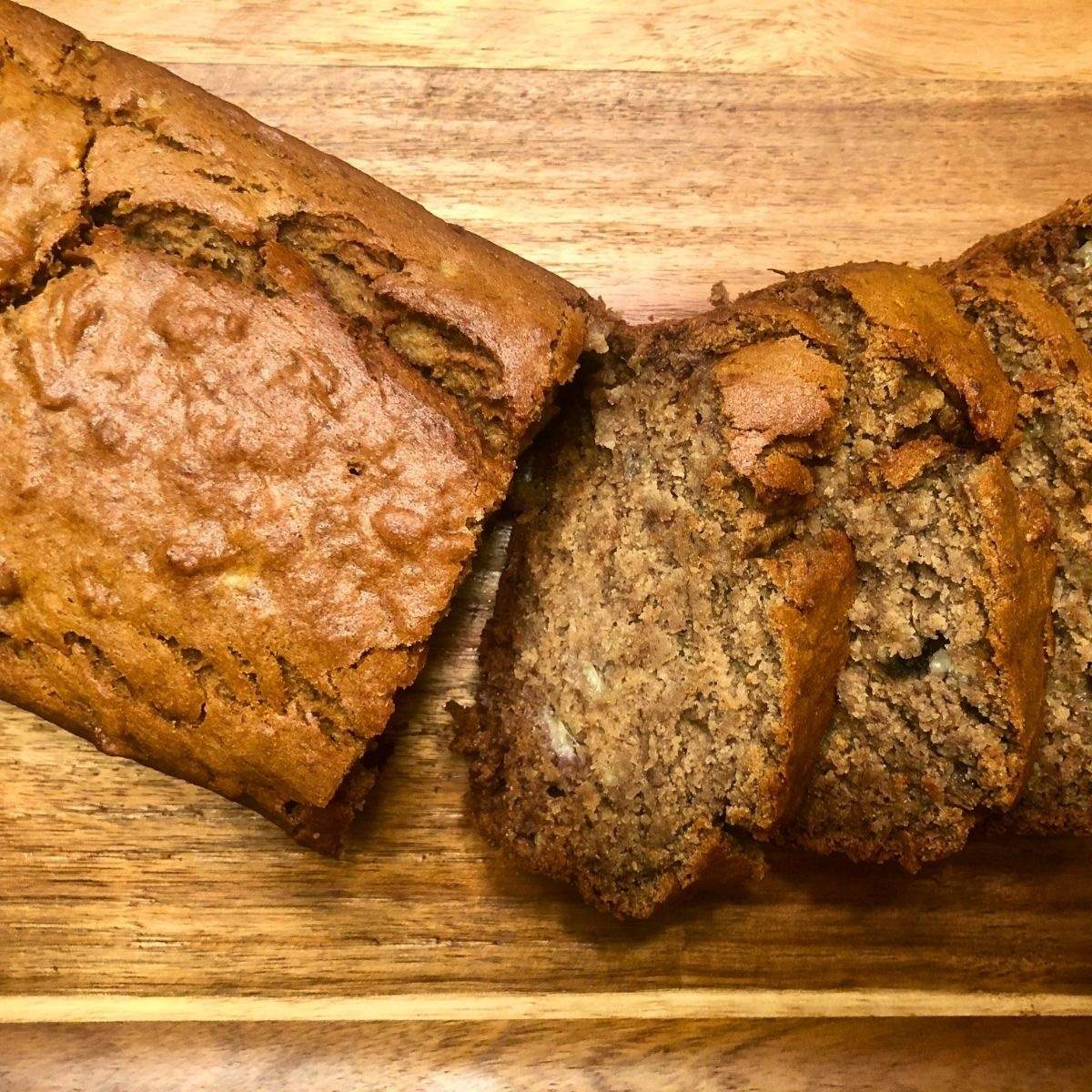 A loaf of brown banana bread, sliced into several pieces of delicious, soft, and moist banana bread.