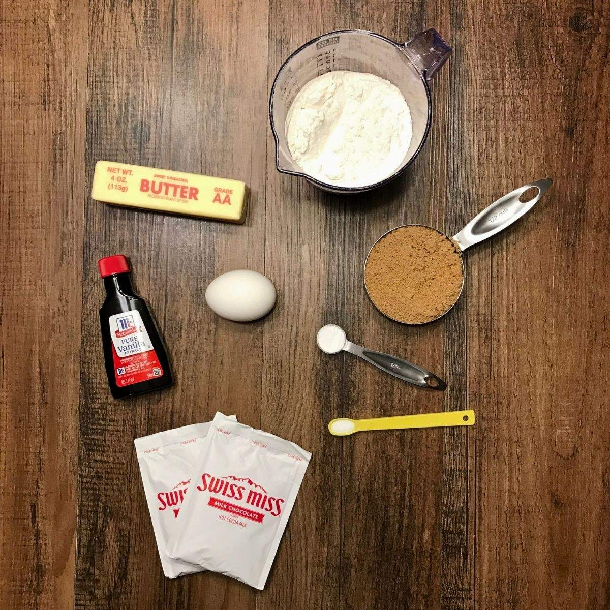 The simple ingredients needed for this hot cocoa cookies recipe - 2 packets of Milk Chocolate Hot Chocolate Mix, Vanilla Extract, Butter, an Egg, Flour, Brown Sugar, Salt, and Baking Soda.